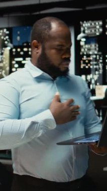 Dikey Video Siyah adam bilgisayardaki raporlardan ana noktaları not etmeden ve çıkarmadan önce arşivlenmiş belgeleri inceliyor. Geç saatlerde belgelenen analist