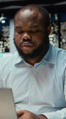 Dikey Video Siyah çalışanı, kurumsal çalışma sahasında geceleri düzenli planlama yapar, yeni fikirler üretir ve zorlu bir soruna çözüm bulmak için iş görünümlerini yansıtır.