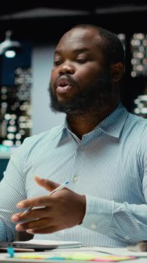 Dikey Video Siyah iş danışmanı mesai bitiminden sonra online bir video görüşmesine katılıyor, hissedarlarla internet üzerinden görüşmelerine katılıyor. Profesyonel adam ağ kurma oturumunda insanlarla iletişim kuruyor