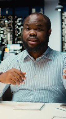 Dikey Video Siyah iş adamı karanlık ofisten çevrimiçi video görüşmesi yapıyor, web kamerasında göz teması kuruyor. Anlamlı konuşmalar için toplantıya katılmak, yatırımcılarla yakınlık kurmak