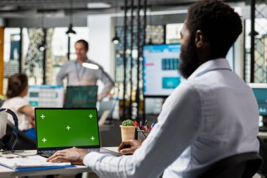 Siyahi finans uzmanı şirket harcamalarını laptopta inceleyerek yeşil ekranı ofiste izole etti. Krom anahtar ekran aygıtı üzerinde iş verilerini gözden geçiren Afrikalı Amerikalı çalışan.