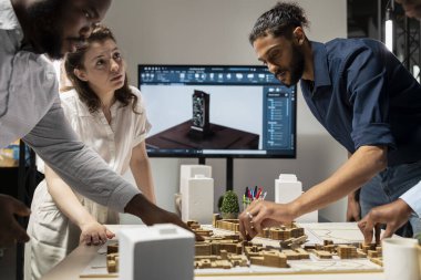 Çeşitli meslektaşlar, iş hedeflerini yenilik ve emlak sektöründe sürdürülebilirlikle dengelemek üzere bir emlak yatırım fırsatı için yapısal planları gözden geçiriyorlar. Şehir planlaması.