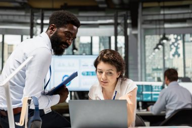 Çevrimiçi pazarlama stratejileri kullanarak proje geliştirme konusunda Afrika kökenli Amerikalı iş adamı kadın asistanla işbirliği yapıyor. Siyahi erkek ve beyaz kadın şirket gelişimini artırmak için takım çalışması.