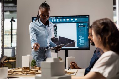 Afrika kökenli Amerikalı emlak mühendisi meslektaşlarıyla ortak bir oturum sırasında site hazırlama planı ve 3D modeller üzerinde imar düzenlemeleri sunuyor. Şehir planlama için gelecekteki konut girişimi.