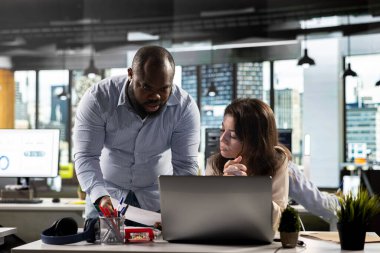 Profesyonel iş adamları risk değerlendirmesi için belge ve grafikleri analiz ederler. Modern ofiste rapor yazma, tahmin etme ve performans ölçümlerinde işbirliği yapan çeşitli çalışma ekipleri.