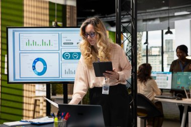 Kadın işletme yöneticisi, takımının performans numaralarını inceleyerek KPI ölçümlerini hedef belirleme ve iş başarıları açısından değerlendirdi. Yönetmen bir başarı öyküsüyle güçlendi..