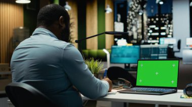 Ofisteki siyahi erkek çalışanlar mesai saatleri dışında laptopta yeşil ekran kullanıyor, yeni toplantılar düzenliyor ve haftalık gündemi planlıyorlar. Bir şirket projesi için işletme yönetimi görevleri.