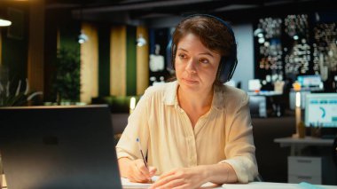 Uzaktan kumandalı bir web sitesine katılan bir kadın dizüstü bilgisayar ve kulaklık kullanarak katılımcılarla iletişim kuruyor. Göz temasını sürdürmek, iletişim kurmayı teşvik eden bir sohbette fikir alışverişinde bulunmak. Kamera A.