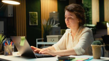 Gergin iş kadını, sırtı ve boyun kaslarını esnetiyor koltuk duruşunu ve boyun sertliğini düzeltiyor. Rahatsızlık ve yorgunluk. Kamera B.