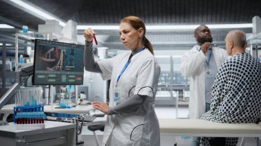 Araştırmacı kan örneklerini inceliyor ve klinik bir deney için hastayı gözlem altında tutuyor. İlaç dozajını değerlendiriyor ve reaksiyonları inceliyor. Tıbbi keşifte ilerleme var. Kamera A.