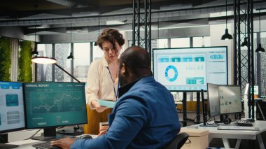 İşyeri destek çalışanı dosya ve sözleşmelerle dolu bir teslimat arabasını taşıyor. Muhasebe işleri için arşivlenmiş evrakları getiren Afrikalı Amerikalı yöneticiye yardım ediyor..