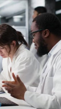 Dikey video laboratuarı kimyagerleri test tüpündeki sıvıları inceleyip klinik deneyler sırasında buluşlar arıyorlar. Araştırma tesisi çalışanları kimyasal tüpleri karşılaştırıp test ediyorlar.