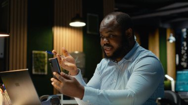 İş adamı, akıllı telefondaki video konferansı sırasında personelle etkileşime geçerek brifing oturumu için son rapor verilerini paylaşıyor. Çalışma saatleri dışında web sayfasında ortak toplantı.