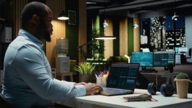 Erkek maliye analisti gelir raporları için ticaret hesapları ve arşivlenmiş verileri inceleyerek, kaynak tahsisini planlamak ve iş hedeflerini mali başarıyla hizalamak için dijital grafikler kullanarak.