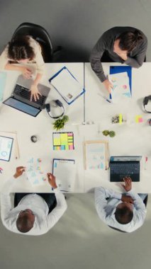 İş görüşmesi sırasında iş görüşmelerine katılan iş ekibine dikey video yukarıdan aşağı zoom yap. Çalışanlar ofis ortamında finans verilerini ve performans raporlarını analiz etmek için dizüstü bilgisayar kullanırlar