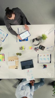 Vertical Video Top bir şirket toplantısı sırasında finans ve bütçe danışmanlığı yapan iş adamlarının yakınlaşmasına bakıyor. Personel, hedefleri belirlemek ve planlamak için belge, diyagram ve raporları analiz eder