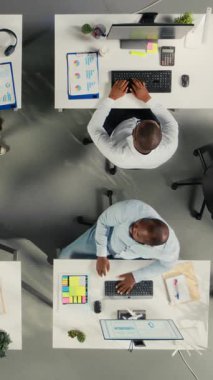 Rapor yazarken iş adamlarının diyagramları gözden geçirdiği dikey video yukarıdan aşağı görünüm yakınlaştırması. Çokuluslu şirketlerdeki meslektaşlar, pc ve görsel veri araçları kullanarak içgörü ve koordinasyon görevlerini paylaşırlar