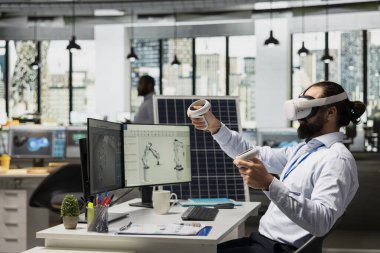 Yenilenebilir enerji şirketinde çalışan teknisyen güneş panelleri geliştirmek için VR kulaklık kullanıyor. Ekolojik güneş paneli montaj işleri üretmek için sanal gerçeklik simülasyonu kullanan işçiler