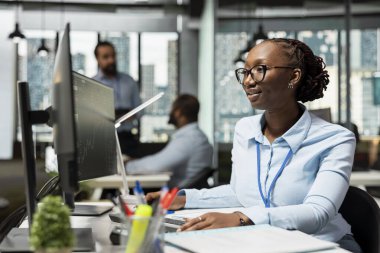 Ticaret stratejilerini değerlendirmek ve kayıpları en aza indirmek için bilgisayarı kullanan risk analisti. Mali piyasalardaki dengesizliği değerlendirmek için veri raporlarını kullanan aksesuar firmasındaki Afrikalı Amerikalı kadın.