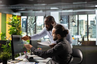 Çok uluslu bir şirkette çeşitli meslektaşlar analitik, diyagram ve performans ölçümlerini gözden geçirir. İş adamları kurumsal planlamayı geliştirmek için görüşleri ve tahminleri paylaşıyor.