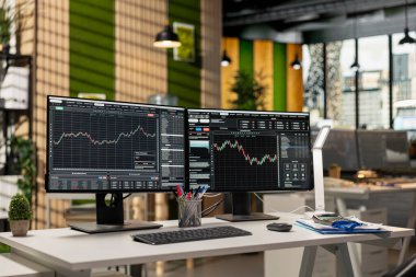 Forx şirketinin ofisindeki bilgisayar monitörleri borsa fiyat grafiklerini gösteriyor. Prop firmasının çalışma alanında hisse senedi piyasası finansal yazılım platformu arayüzünü gösteren PC ekranları