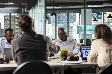 Şirket çalışanları belgeleri ve performans raporlarını inceliyor. Profesyonel bir ofis ortamındaki meslektaşlar planlama, projeksiyonlar ve pazar araştırma geliştirmesinde işbirliği yaparlar..