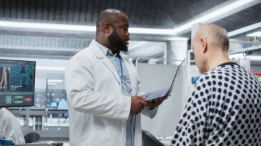 Siyahi bilim adamları bir sağlık enstitüsünde yapılan bir ilaç denemesi sırasında hastaların tepkilerini gözlemliyor, tıbbi ilerlemede güvenli dozaj seviyelerini sağlamak için verileri kaydediyor ve hayati değerleri izliyor. Kamera B.