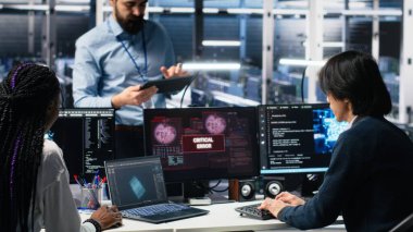 Veri Merkezi Yöneticisi, Yapay Zeka kullanırken kritik hatayı düzelten programcıları koordine ediyor. Sunucu odası lideri, yapay zeka ve kamera A 'yı kullanarak arızalı açılır pencereyi tamir eden işçilere nezaret ediyor.