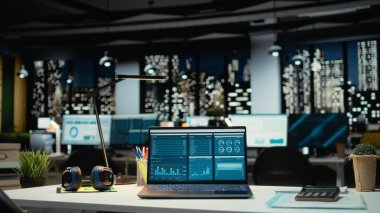 Gece geç saatlerde boş bir ofiste veri raporlarını gösteren modern dizüstü bilgisayar performans ölçümleri ve tahmin grafikleri. İşletme yönetimini yansıtacak teknolojiyle donatılmış şirket çalışma alanı.