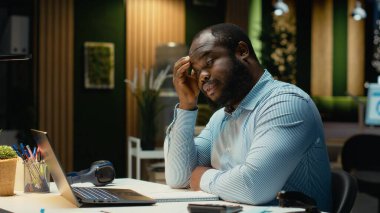 Afrikalı Amerikalı adam diğer masalara bakıyor ve ofiste yalnız olduğunu fark ediyor, fazla mesai yapıyor ve tükenmişlerle uğraşıyor. Uykucu aşırı yüklenmiş kişi gece geç saatlere kadar çalışıyor..