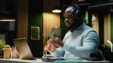 Zenci işadamı müzik dinler ve üst vücut kaslarını geliştirir. Kompleks işleri bitirmek için gece geç saatlerde fazla mesai yapar. Kulaklıkları bırakıp işini bitiriyor. Kamera B.