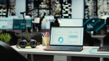 Geceleri boş şirket yönetim kurulu odası. Bilgisayarında dijital performans ölçümleri, grafikler ve projeksiyonlar var. Çok uluslu bir şirkette modern ofis işletme yönetimini yansıtır.