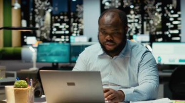 İş yerindeki Afrikalı Amerikalı adam yoğun konsantrasyonda oturup karar vermeyi düşünüyor. Mantıklı düşünme ve sezgilerini uygularken dizüstü bilgisayarını kullanmak, zihinsel bulanıklık. Kamera B.