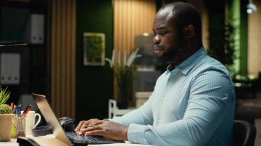 Afrika kökenli Amerikalı çalışanlar gece geç saatlerde ofiste bir özet hazırlıyorlar. Veriler, aylık faaliyet planlayıcısı, iş hedefleri ve gündemi ile bilgi rapor etmektedir. Kamera B.