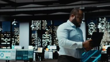 Afrika kökenli Amerikalı iş adamı ofiste duruyor ve çözümler arıyor, düşünceli olarak ve şirket büyümesi için yeni fikirler buluyor. Gece geç saatlerde görevleri öngören bir danışman. Kamera B.