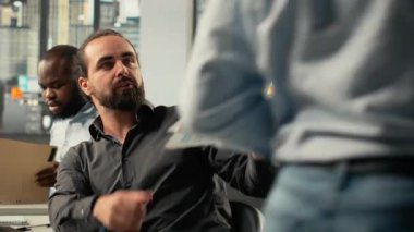 İş adamları, belgeleri kullanarak geliştirme stratejileri ve analizleri tartışıyor. Profesyonel çalışanlar şirket planlamasını geliştirmek için gerekli belgeleri, tahminleri ve görüşleri gözden geçirirler. Kamera B.