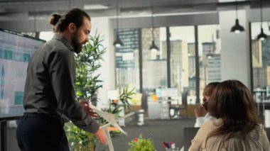 Şirket çalışanları finans, hedefler ve öneriler hakkında görüşmek üzere bir toplantıda bir araya geldiler. Meslektaşlar ve iş arkadaşları proje planlamasına rehberlik etmek için anlayış, belge ve performans ölçümlerini paylaşıyorlar. Kamera B.