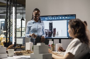 Beyin fırtınası toplantısında 3 boyutlu modeller kullanan çok ırklı mimari geliştiriciler ekibi, yapısal şehir planlaması üzerinde çalışmak üzere mimari yazılım gösteriyor. Kentsel kalkınma için konut projesi.