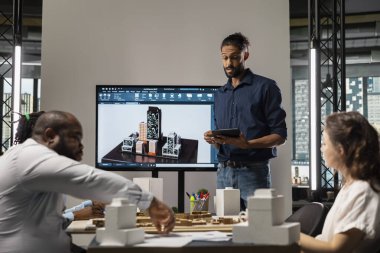 Gayrimenkul uzmanları planlar ve 3D modelleri inceleyen bir ekip toplantısında, konut ve altyapı büyümesini hedefleyen büyük ölçekli bir kentsel kalkınma projesinin planlanmasına son verdiler..