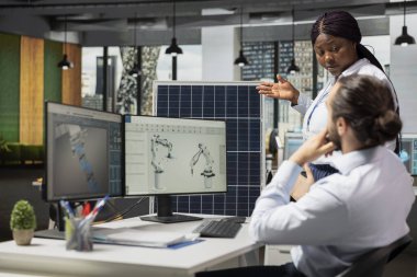 Mühendisle güneş paneli hücrelerini ve düşük karbon ayak izi tasarımlarını tartışıyor. Ekip lideri ve çalışanı otomatik temiz enerji güneş paneli üretimi için robotik kol sistemleri geliştiriyor