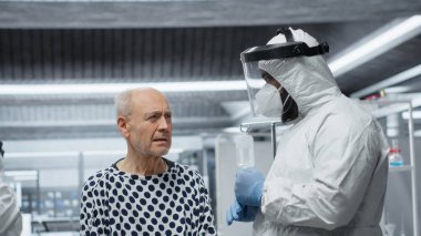 Karantina tesisindeki siyah doktor salgın sırasında hastalara tıbbi bakım sağlayarak, küresel salgın hastalıkların önlenmesi için hastalık, ilaç tedavisi ve aşı testleri hakkında veri topluyor. Kamera B.