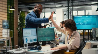 Çeşitli erkek ve kadınlar iş yerinde beşlik çakarak birbirlerini tebrik ediyorlar, ofis arkadaşları başarılı proje tamamlanmasının keyfini çıkarıyorlar. Çok uluslu şirkette günlük görevler.