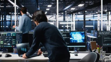 Veri merkezine gelen teknisyen, üretici yapay zeka yardımıyla kodlama yapıyor. BT uzmanı masada oturuyor, yapay zeka üzerinde çalışıyor büyük dil modeli çözme görevleri, kamera A