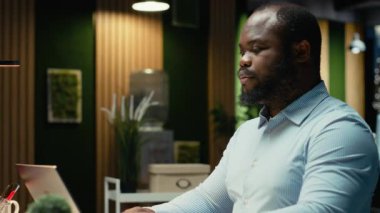 Siyah iş adamının portresi, not defterine veri yazmadan önce, geceleri ofiste oturmadan önce eleştirel düşünme ve düzeltme yapar. Önemli fikirleri fazla mesai için belgeliyorum. Kamera B.