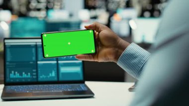 Modern uzayda yeşil ekranlı cep telefonuyla çalışan Afrikalı Amerikalı bir adam strateji odasında online görüşleri kontrol ediyor. İş yönetimiyle ilgilenen erkek genel müdür. Kamera B.