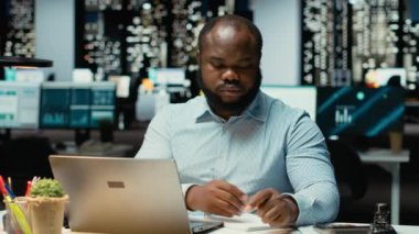 El yazısı özeti hazırlayan Afrikalı Amerikalı bir adam. Ofiste saatler sonra son gelişmeleri yazıyor. Günlük planlama, iş hedefleri ve gündem belgelerinin sağlanması. Kamera B.