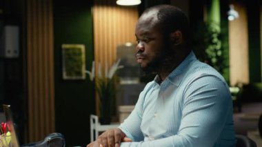 Gergin bir siyah adam yoğun iş yükü yüzünden sinirlenir, saatler sonra hüsran ve rahatsızlık içinde çalışır. Endişeli huzursuz çalışan karanlık ofiste bunalıyor. Kamera B.