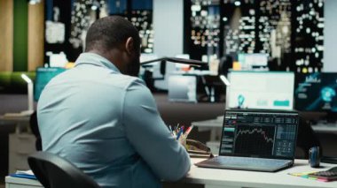 Küresel piyasa trendlerinin yükselişini kutlayan memnun siyah adam, kripto para biriminin başarısı ve para kazanmasıyla mutlu ve neşeli hissediyor. İş geliştirme hedefleri saatler sonra. Kamera B.