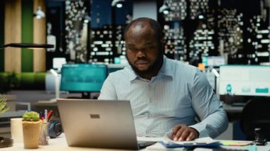 Kendine güvenen erkek çalışanlar, gece geç saatlerde karanlık ofiste tek başlarına yeni bir proje üzerinde çalışıyorlar. Adam bilgisi ve aylık hedefleri kontrol ediyor. Kamera B.