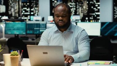 Afrika kökenli Amerikalı analist, çalışma saatleri dışında bir sorun için olası sonuçlar üzerinde kafa yoruyor. Mantıksal çıkarım ve gözlem ile projeksiyonları değerlendirmek için yoğun bir konsantrasyon. Kamera B.